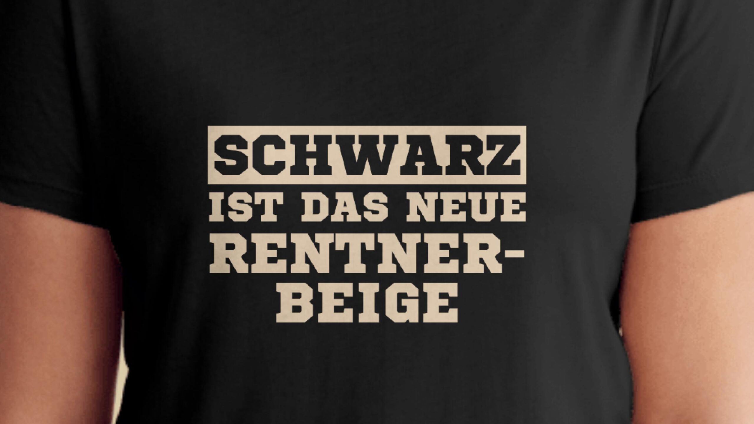 Ausschnitt: Brust eines Menschen, der ein schwarzes T-Shirt trägt mit der Aufschrift: Schwarz ist das neue Rentnerbeige.